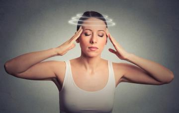 Síntomas del tinnitus Una mujer con síntomas de mareo se sujeta las sienes