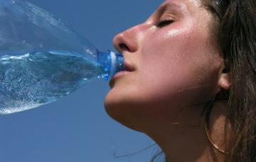 Cómo prevenir un golpe de calor Una mujer bebe agua al aire libre