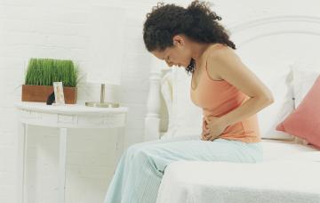 Síntomas de un aneurisma Mujer se sujeta el abdomen con gesto de dolor