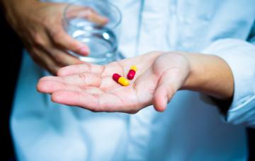 Tratamiento farmacológico del insomnio Un hombre sujeta en su mano unas cápsulas para tratar el insomnio