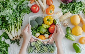 El reto de las 30 plantas a la semana Primer plano de las manos colocando verduras en una bolsa