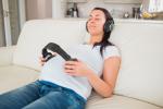 Una embarazada escucha música con unos auriculares sobre su vientre