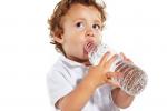 Un niño pequeño bebe agua de una botella
