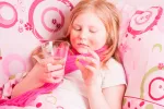 Niña tomando medicamentos Niña enferma en la cama tomando medicamentos