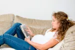 El 68% de las embarazadas no hace suficiente ejercicio Embarazada sedentaria leyendo en el sofá