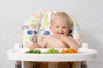 Expertos recomiendan el método baby-led weaning Un bebé en la trona come trozos de verduras cocidas que tiene delante