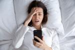 Mujer mirando con angustia el dispositivo móvil creyendo que no ha dormido suficiente