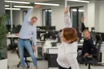 15 minutos de ejercicio en el puesto de trabajo benefician la salud Grupo de trabajadores haciendo ejercicio en la oficina
