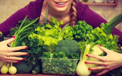 Fibermaxxing: pros y contras de maximizar tu ingesta de fibra Mujer joven sosteniendo entre sus brazos un monto de vegetales distintos