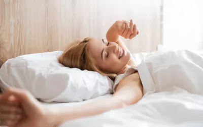 Quedarse en la cama más tiempo en vacaciones Mujer rubia despertando en la cama en mañana soleada de verano