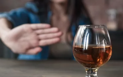Mujer rechaza una copa de alcohol Mujer hace un gesto de rechazo con la mano a una copa de alcohol