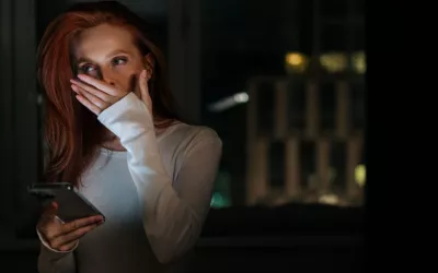 Mujer con el móvil en la mano bosteza antes de ir a dormir Mujer en una habitación a oscuras bosteza con el móvil en la mano