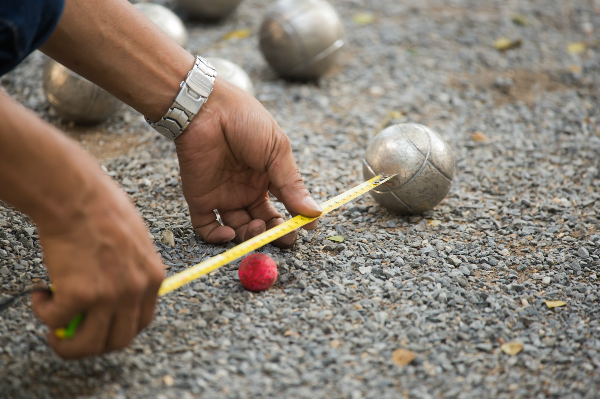 Una persona midiendo la distancia entre el boliche y una bola