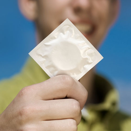 Chico mostrando un preservativo masculino