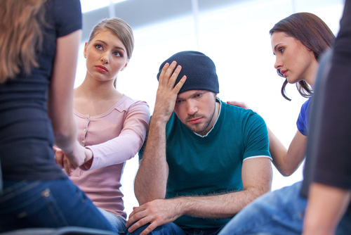 Un joven es consolado por sus amigos