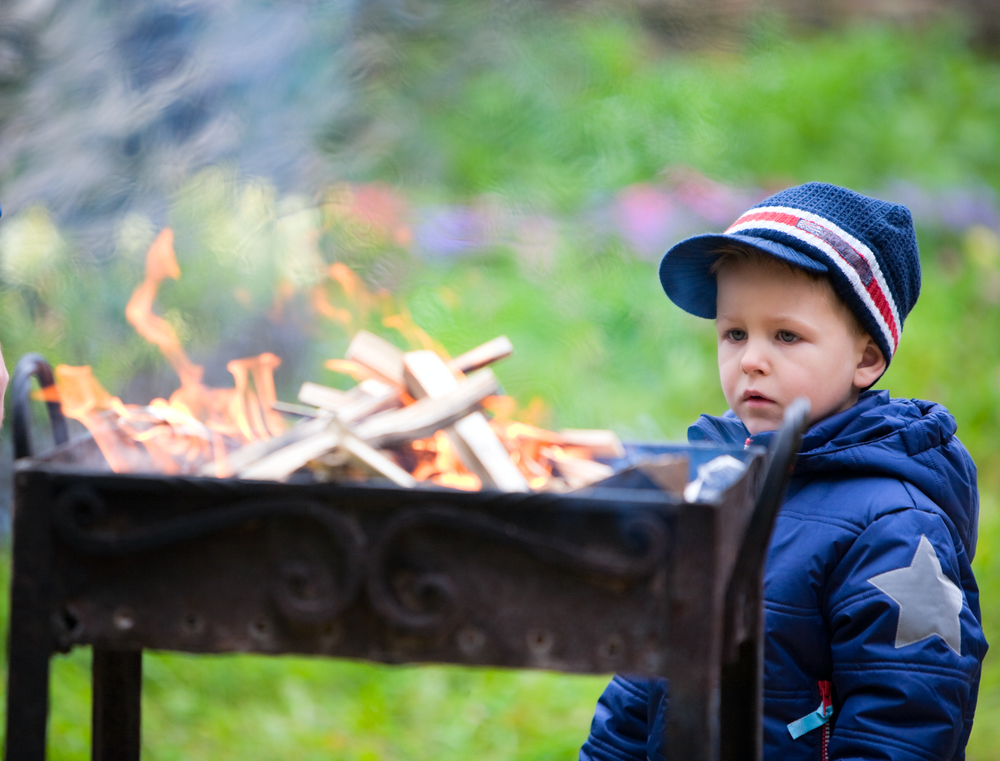 Niño pequeño contemplando el fuego de una barbacoa