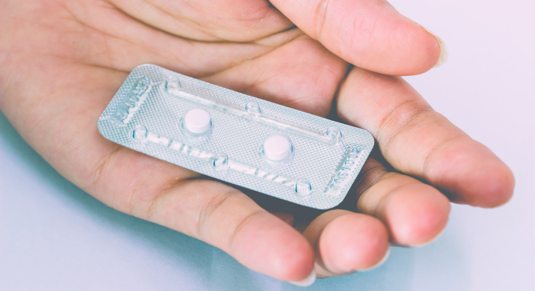 Chica en la mano con la píldora poscoital
