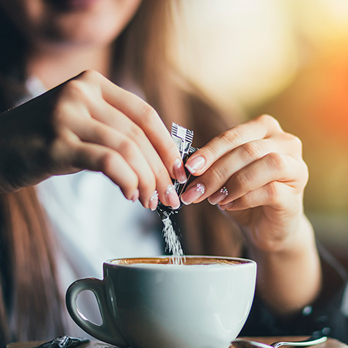 Mujer usando edulcorantes en su café