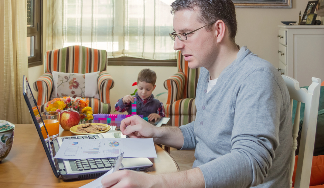 Padre teletrabajando junto a su hijo pequeño