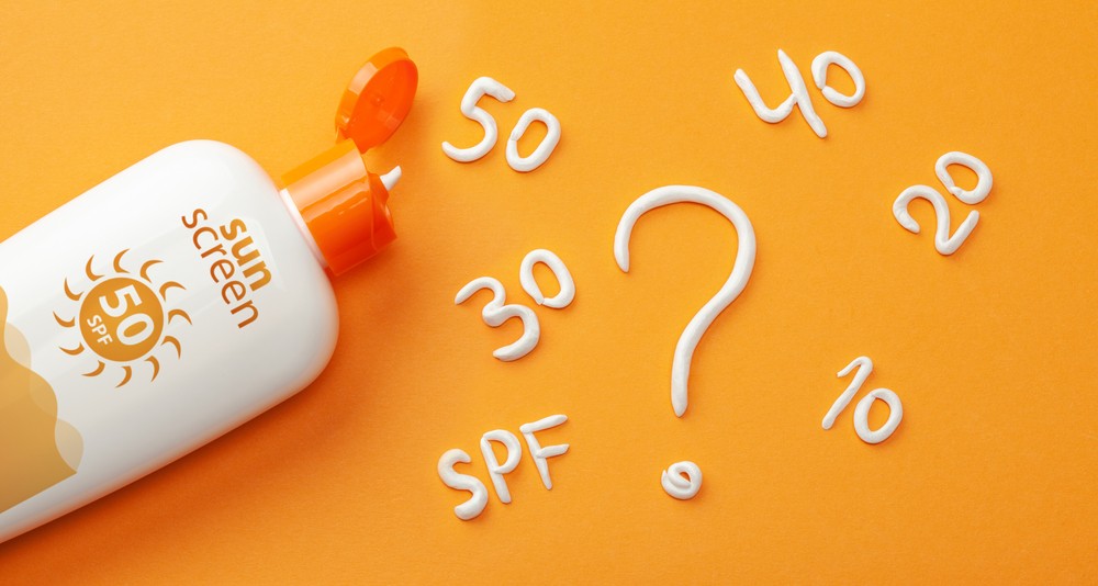 Dudas sobre SPF de la crema solar Crema de protección solar y crema blanca en forma de signo de interrogación y números SPF