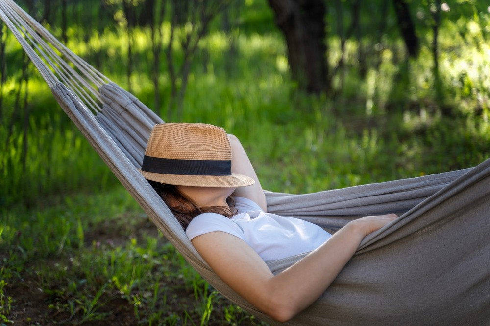 Dormir en verano en una hamaca Mujer echando siesta en una hamaca en el jardín