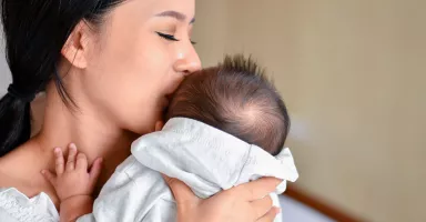Madre abrazando a su bebé con síndrome de Menkes