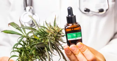Doctor sostiene unas hojas de marihuana y un bote de CBD