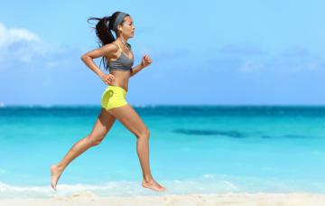 Una joven corre descalza por la playa