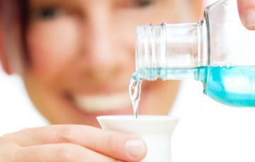 Mujer dosifica un colutorio para tratar sus aftas bucales