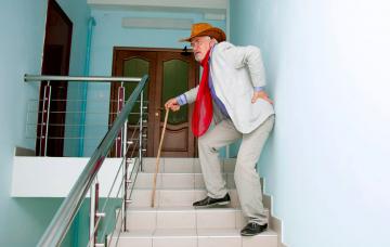 Causas y epidemiología de la enfermedad de Paget Un hombre mayor sube con dificultad las escaleras apoyado en un bastón