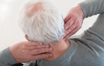 Complicaciones de la enfermedad de Paget Un hombre mayor se toca el cuello dolorido