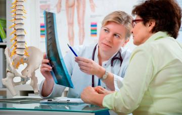 Diagnóstico de la enfermedad de Paget Una doctora comenta una radiografía con la paciente