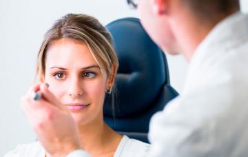 Un oftalmólogo examina los ojos de una paciente