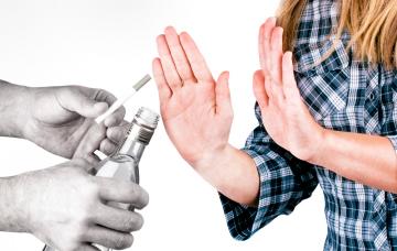 Una mujer rechaza la bebida alcohólica y el cigarrillo que le ofrecen