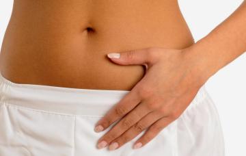 Imagen del vientre de una mujer con la mano apoyada sobre el mismo