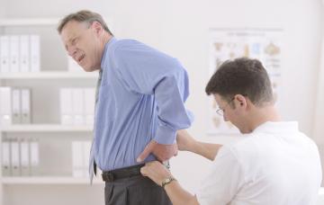 Síntomas del cáncer de próstata Doctor analizando a un hombre con dolor en la parte inferior de la espalda