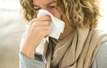 Mujer con gripe se suena la nariz