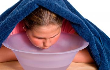 Niña tratándose con vahos la congestión nasal Tratamiento de la congestión nasal