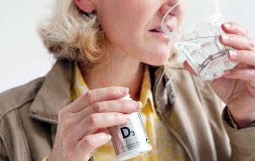 Mujer bebe agua para tragar un medicamento