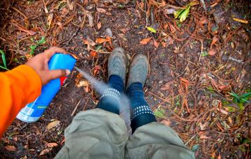 Persona aplicándose un spray para prevenir las picaduras de insectos