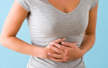 Síntomas de una úlcera Mujer se toca el abdomen dolorido a causa de una úlcera