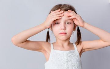 Una niña pálida se toca la frente