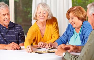 Un grupo de personas mayores juega al dominó