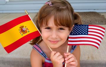Crianza bilingüe Niña sosteniendo una bandera española y otra estadounidense