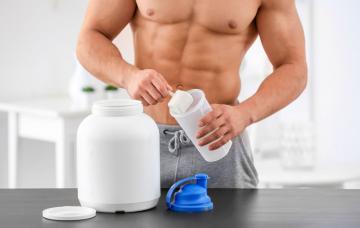 Gainers, ganadores de peso Hombre con músculos tomando suplementos para el deporte llamados gainers