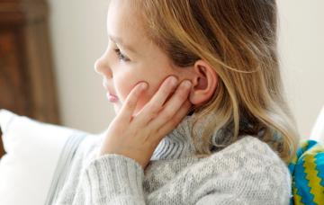 Niña se toca el oído dolorido