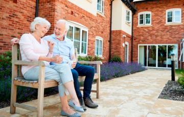 Senior cohousing, vivienda colaborativa para mayores Pareja de personas mayores junto a una vivienda colaborativa