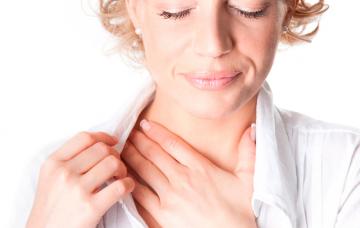 Una mujer se toca el cuello con gesto de dolor