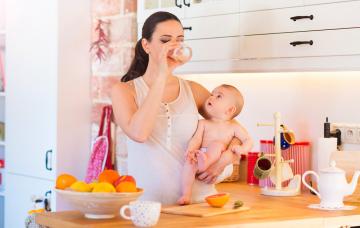 Mujer lactante en la cocina con su bebé