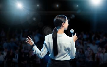 Mujer hablando en un auditorio cara al público